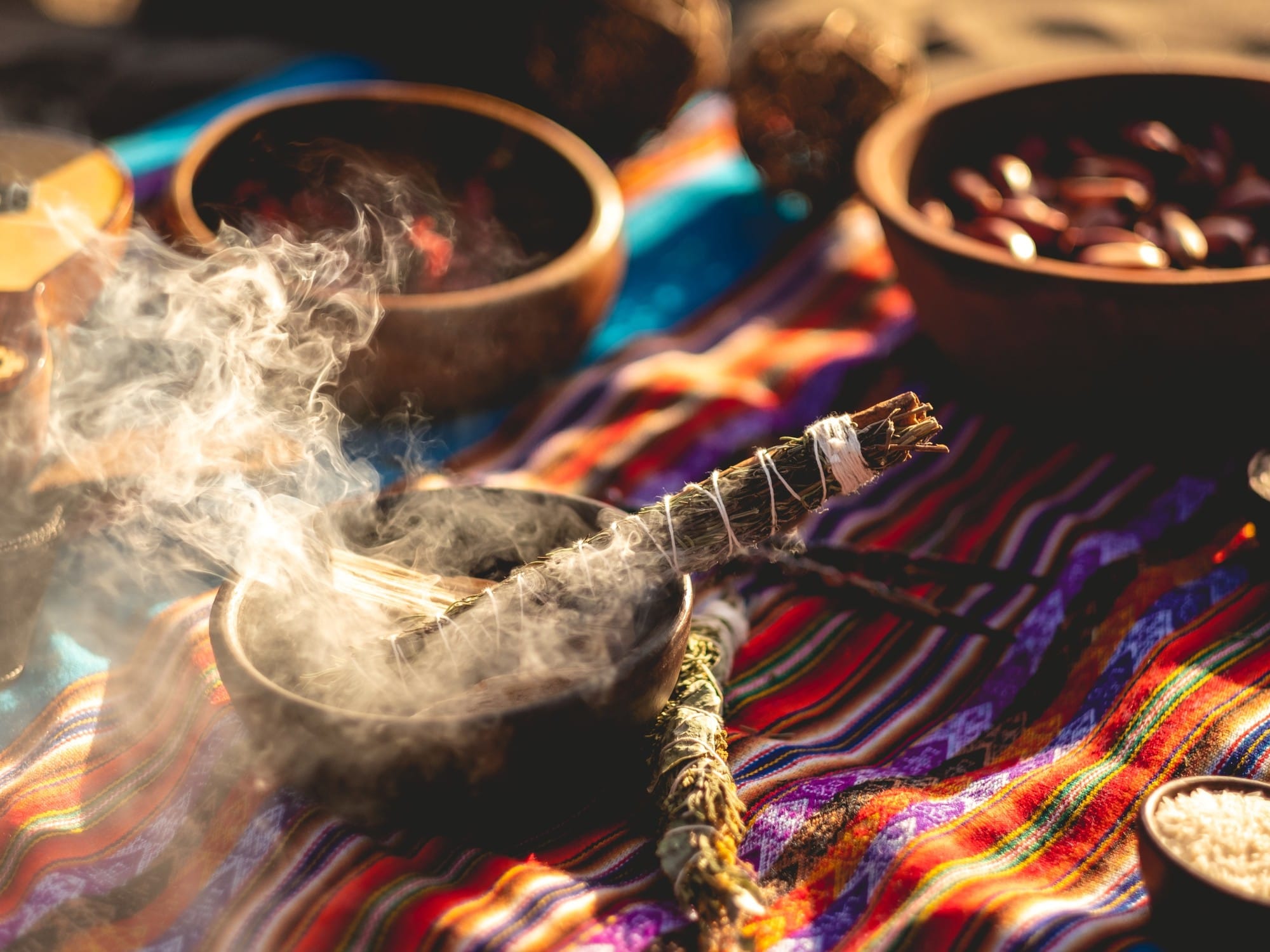 Sahumo encendido junto a cuencos sobre un tejido ceremonial